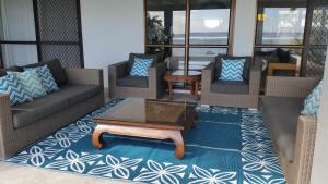 a living room with couches and a coffee table on a rug at Sunset Quay in Rarotonga