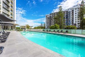 a swimming pool with chairs and a building at Mantra Sierra Grand in Gold Coast