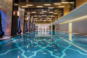 a swimming pool in a hotel with a blue tile floor at Wanda Realm Nanjing in Jiangning