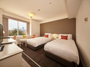 a hotel room with two beds and a desk at Tokyo Prince Hotel in Tokyo