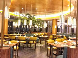 a restaurant with tables and yellow chairs and chandeliers at Grand Soll Marina Hotel in Tangerang