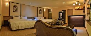 ein Hotelzimmer mit einem großen Bett und Stühlen in der Unterkunft Dawn Of Tarot B&B in Taitung