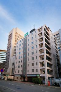 a large white building with a street sign on top at Washington R&B Hotel Hakata Ekimae 1 in Fukuoka