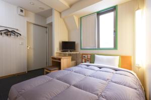 una camera con un grande letto viola e una finestra di R&B Hotel Kobe Motomachi a Kobe