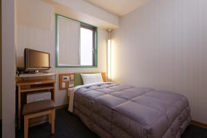 a bedroom with a bed and a desk with a television at R&B Hotel Kobe Motomachi in Kobe