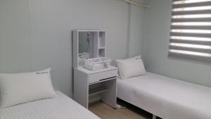 a white room with two beds and a mirror at MK Guesthouse in Busan
