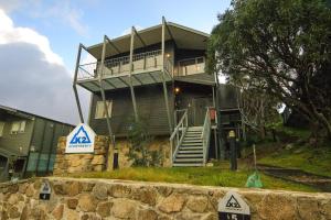 a large house with a porch and stairs in front of it at Apartment K2 05 in Mount Buller