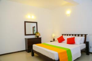 Miyura Holiday Bungalow في كاندي: غرفة نوم مع سرير مع أوراق ملونة ومرآة