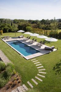 a swimming pool with chairs and umbrellas on a lawn at Domaine Mejan in Paradou