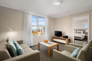 a living room with a couch and a television and a bed at Quest Wollongong in Wollongong