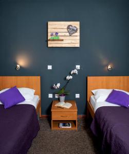a bedroom with two beds and a table with flowers at Hotel Fala in Zagreb