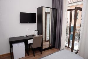 een kamer met een bureau, een televisie en een raam bij Guest House Gantiadi in Batoemi