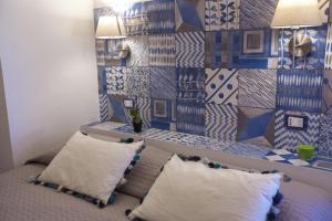 a bedroom with a bed with two pillows and a tiled wall at Grace's Place in Scopello