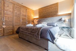 1 dormitorio con 1 cama grande y paredes de madera en Chalet O New!, en Ortisei