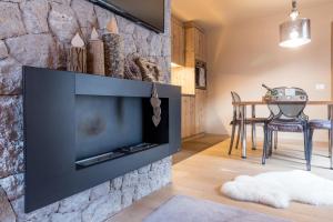 a living room with a large television mounted on a stone wall at Chalet O New! in Ortisei