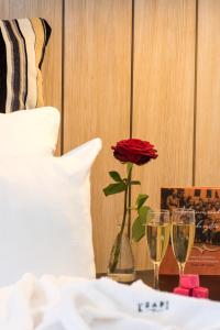 a vase with a rose and two glasses on a table at Hotel Krapi in Tuusula
