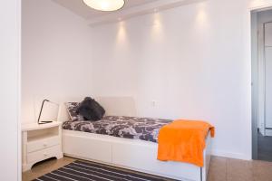 ein weißes Zimmer mit einem Bett mit einer orangefarbenen Decke in der Unterkunft Two-Bedroom Apartment Diosa Tanit in Alicante