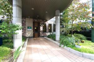 uma entrada para um edifício com colunas e plantas em R&B Hotel Nagoya Sakae Higashi em Nagoia