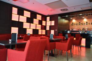 a restaurant with red chairs and a bar at Hotel Arena in Trnava