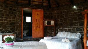 a bedroom with two beds and a stone wall at Amanzi Empilo Bungalow in Rhodes