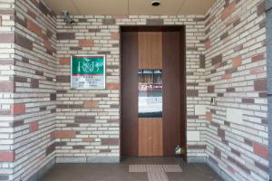 R&B Hotel Nagoya Nishiki في ناغويا: باب في جدار من الطوب مع علامة عليه