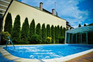 a swimming pool in front of a building with trees at BL.Apartmanház II. in Szeged