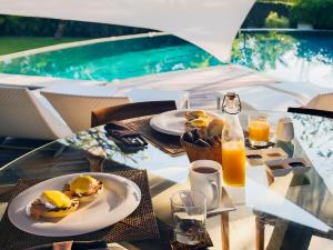 a table with plates of food and a bottle of orange juice at The Layar - Designer Villas and Spa, CHSE Certified in Seminyak