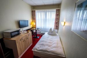 a hotel room with a bed and a television at Sachsenwald Hotel Reinbek in Reinbek