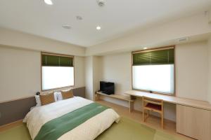 a bedroom with a bed and a desk and two windows at Hotel Showmeikan in Mishima