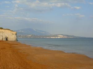 a sandy beach with the ocean and mountains in the background at Gouna's Aparts in Xi
