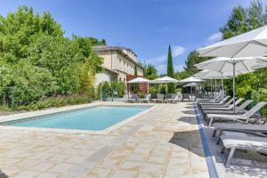 a swimming pool with lounge chairs and umbrellas at Hotel Estelou in Sommières