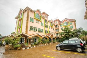 a car parked in a parking lot in front of a building at Casa Miltu Hotel in Kampala