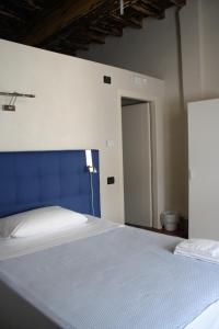 a bedroom with a large bed with a blue headboard at Palazzo Sacco Hostello Fossano in Fossano