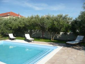 een zwembad met twee stoelen en een tafel en enkele bomen bij Villa Niceta in Zadar