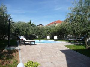 een zwembad met twee stoelen en een tafel naast bij Villa Niceta in Zadar