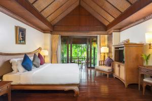 a bedroom with a bed and a television in a room at Nora Beach Resort & Spa - SHA Extra Plus in Chaweng