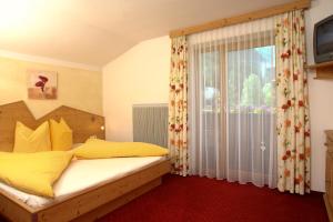 a bedroom with a bed with yellow pillows and a window at Alpenecho in Neustift im Stubaital