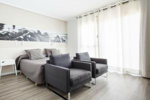 ein Schlafzimmer mit 2 Stühlen und einem Bett und einem Gemälde in der Unterkunft Residencia Universitaria Campus del Mar in Barcelona