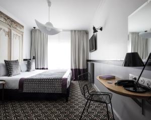 ein Hotelzimmer mit einem Bett und einem Schreibtisch in der Unterkunft Hotel Malte - Astotel in Paris