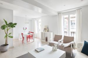 een witte woonkamer met een tafel en stoelen bij Carretas Apartments in Madrid