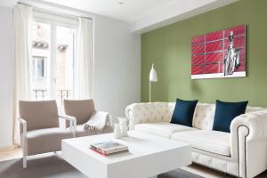 een woonkamer met een witte bank en stoelen bij Carretas Apartments in Madrid