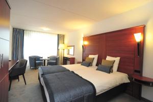 ein Hotelzimmer mit einem großen Bett und einem Schreibtisch in der Unterkunft Hotel Zuiderduin in Egmond aan Zee