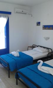 two beds in a room with blue sheets and towels at Vigles in Adamantas