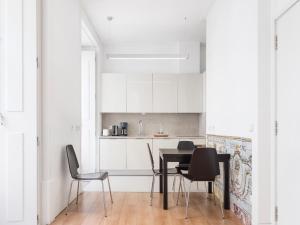 uma cozinha branca com uma mesa preta e cadeiras em Lisbon Serviced Apartments - Baixa em Lisboa