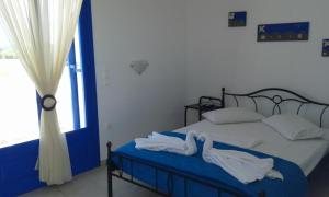 a bedroom with a bed with white sheets and a window at Vigles in Adamantas