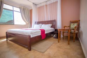 a bedroom with a bed and a table and a window at Eight Winx Hotel in Kampala