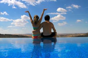 un hombre y una mujer sentados en el borde de una piscina en Casas Rurales Planeta Chicote, en Zafra de Záncara