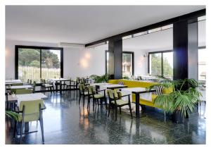 a dining room with tables and chairs and windows at Hotel Eetu - Adults Only in Begur