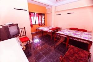 a living room with two tables and a tv at Pleasant Inn in Cochin