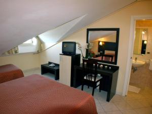 Hotel Europa Park في ليدو دي سبينا: غرفة نوم مع مرآة ومكتب مع تلفزيون